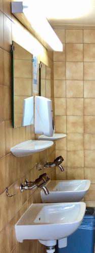 a bathroom with three sinks and a mirror at Auberge Pour Tous in Vallorbe