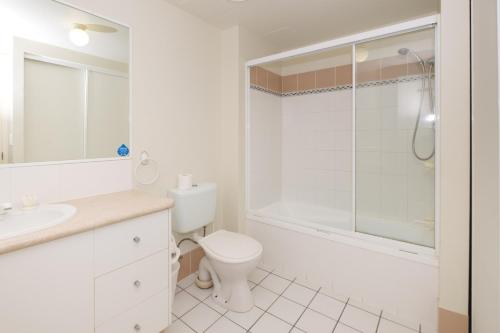 a white bathroom with a toilet and a shower at Sanctuary Lake Apartments in Gold Coast