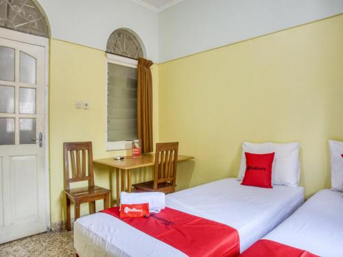 two beds in a room with a table and chairs at RedDoorz Syariah @ Lempuyangan in Yogyakarta