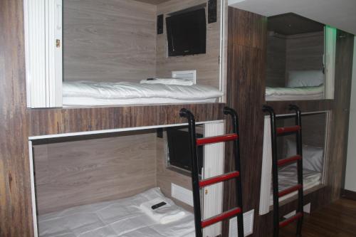 バンコクにあるH-District Boutique Poshotelの二段ベッド2台、テレビが備わる客室です。