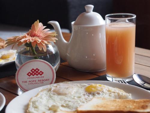een bord eieren en toast en een glas sinaasappelsap bij The Rope Resorts in Darjeeling