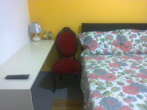 a bedroom with a desk and a red chair next to a bed at Strenua - Las Quintanas in Trujillo