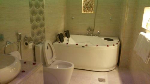 a bathroom with a tub and a toilet and a sink at لؤلؤة الشرق للشقق المخدومة Luluat Al sharq For Serviced Apartment in Hafr Al Baten
