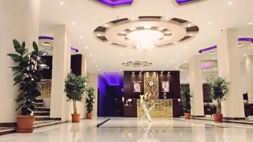 a large lobby with a large chandelier and plants at Al Sharq Hotel in Hafr Al-Batin