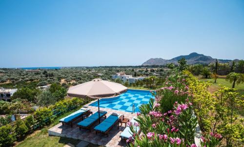 a villa with a swimming pool and an umbrella at Kolymbia Village in Kolymbia