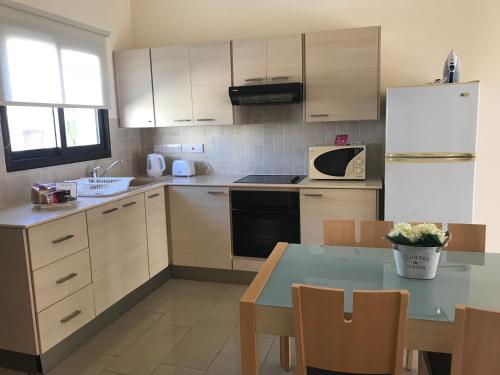 a kitchen with a table and a white refrigerator at Kyklades Resort & Spa in Paralimni