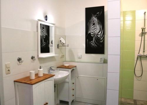 baño con lavabo y una foto de cebra en la pared en Ferienwohnung Lipizzaner en Neußen