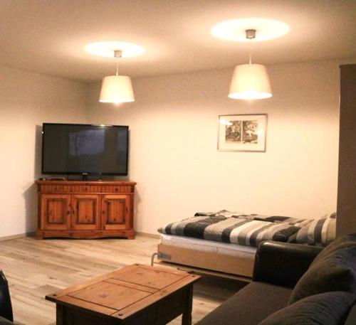 uma sala de estar com um sofá e uma televisão de ecrã plano em Ferienwohnung Lipizzaner em Neußen