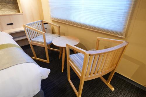 a bedroom with two chairs and a table and a bed at Rinn Shirakawa South in Kyoto