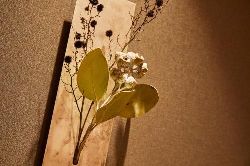 a vase with flowers and leaves on a table at Rinn Shirakawa South in Kyoto