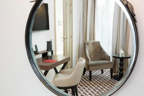 a mirror in a room with a chair and a desk at Hotel Phileas Lazare & Spa - Opera in Paris