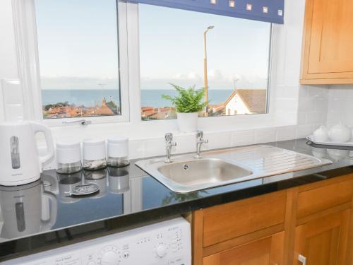 a kitchen counter with a sink and two windows at Bay View House in Colwyn Bay