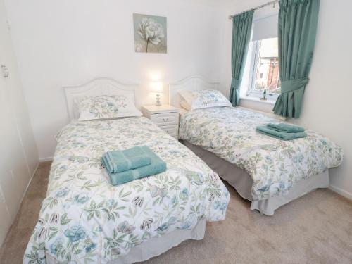 two beds in a bedroom with green curtains at Bay View House in Colwyn Bay