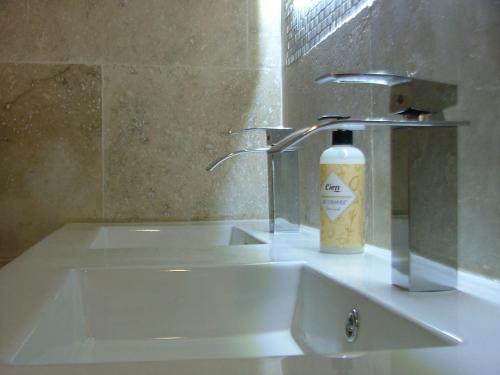 um lavatório de casa de banho com uma garrafa de sabão em le frangipanier em Le Barroux