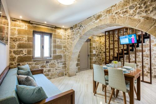 une salle à manger avec un mur en pierre, une table et des chaises dans l'établissement Agarathos Deluxe Homes, à Kíssamos