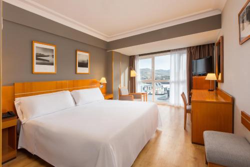 Hotel San Sebastián Orly, Affiliated by Meliá في سان سيباستيان: غرفة نوم بسرير ابيض كبير وتلفزيون