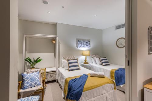 a bedroom with two beds and a chair at Hamptons Retreat on Level 77 Skytower in Brisbane