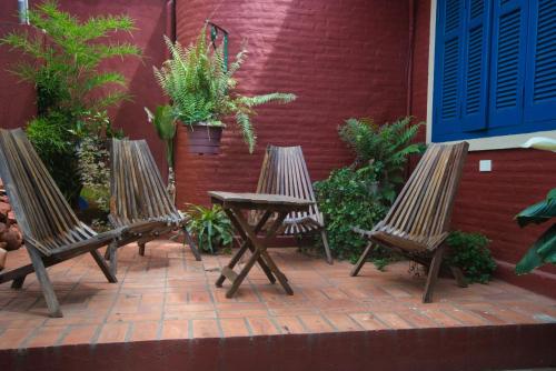 three wooden chairs and a table in front of a building at Vacaciones Aregua CASA VANESSA in Areguá
