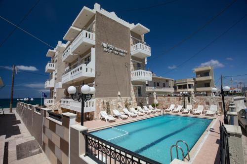 a hotel with a swimming pool in front of a building at Mandy Suites in Kissamos
