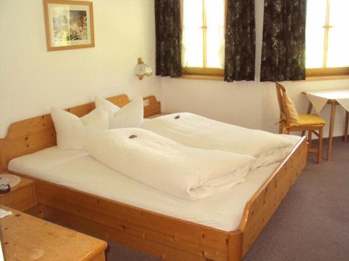 1 dormitorio con cama de madera con sábanas blancas en Haus Alpengruss, en Sankt Leonhard im Pitztal