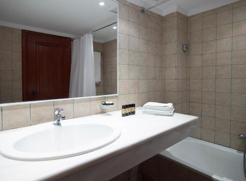 La salle de bains est pourvue d'un lavabo, d'un miroir et d'une baignoire. dans l'établissement Mitsis La Vita, à Rhodes