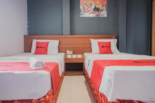 Zimmer mit 2 Betten mit roten und weißen Kissen in der Unterkunft Reddoorz near Nagoya Hill Mall Batam 5 in Batam Center