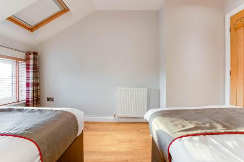 two beds in a room with white walls and a window at The New Mill Apartments in Newcastle upon Tyne