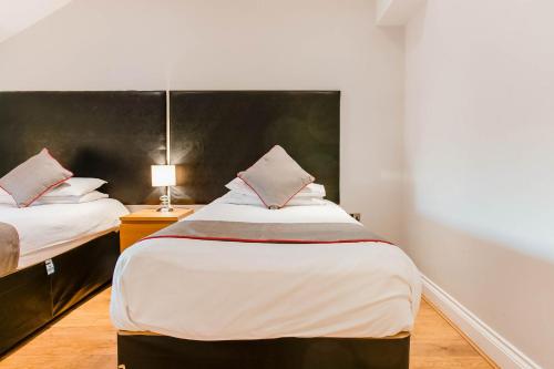 a bedroom with two beds and a headboard at The New Mill Apartments in Newcastle upon Tyne