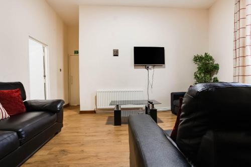 a living room with two black couches and a tv at The New Mill Apartments in Newcastle upon Tyne