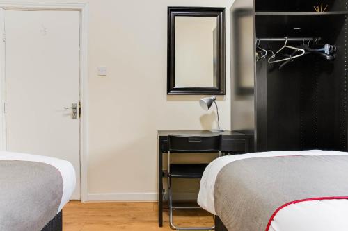 a bedroom with two beds and a table with a mirror at The New Mill Apartments in Newcastle upon Tyne