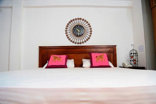 a bedroom with a white bed with pink pillows at D Family Resort in Anuradhapura