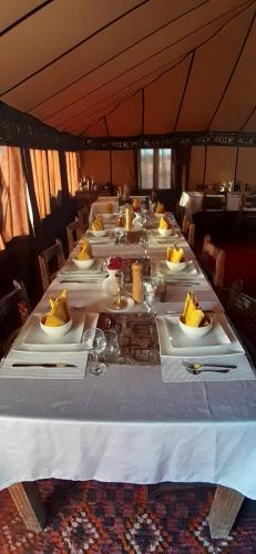 a long table with white plates of food on it at Nomad Camp Merzouga in Merzouga