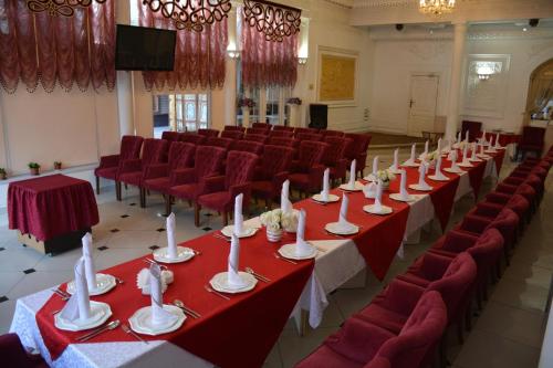 uma sala de conferências com mesas vermelhas e cadeiras vermelhas em Sapar Standart Hotel em Shymkent