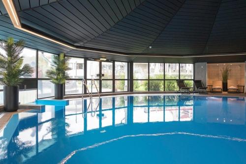 a large swimming pool with blue water in a building at Kl&aelig;kken Hotel in H&oslash;nefoss