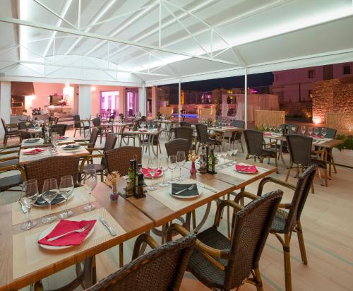 a dining room with tables and chairs with red napkins at My Way Luxury Ibiza Studio - AB Group in Playa d'en Bossa