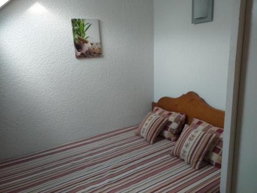 1 cama con 2 almohadas y una foto en la pared en Appartement F2 au domaine des 100 lacs - piscine - sauna - hammam en Cauterets