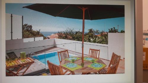 a table with an umbrella next to a swimming pool at Casa Branca in Funchal