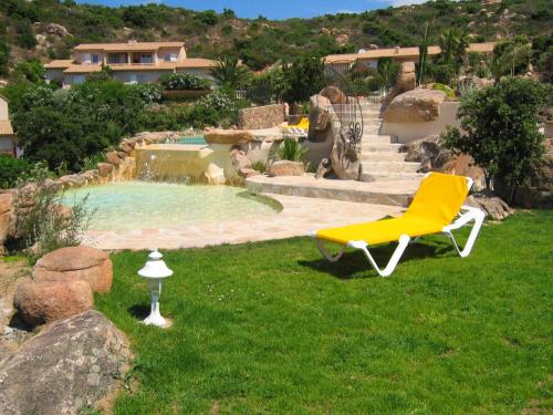 une chaise jaune assise dans l'herbe à côté d'une piscine dans l'établissement Résidence Liccia di Furu, à Porto-Vecchio