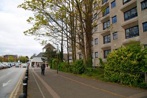 a man walking down a street next to a building at Portfolio Apartments - Stevenage Town Centre in Stevenage