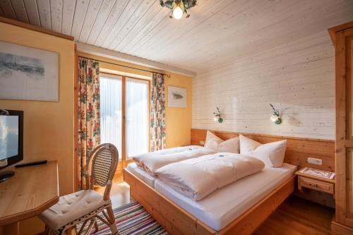 a bedroom with a bed and a desk and a television at Haus Sieglinde in Finkenberg