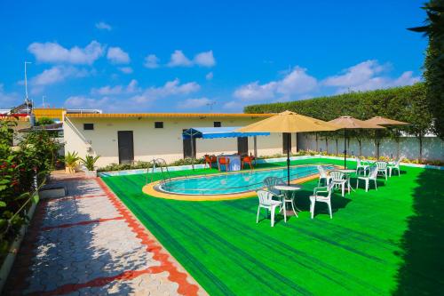 a pool with chairs and umbrellas next to a building at Kalpana Residency in Nellore