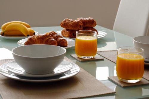 a table with plates and cups of orange juice and pastries at Portfolio Apartments - Stevenage Town Centre in Stevenage