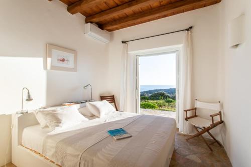 a white bedroom with a bed and a large window at Zen Residence in Lia beach in Kalafatis