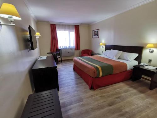ランカグアにあるHotel Diego De Almagro Rancaguaのベッドとデスクが備わるホテルルームです。