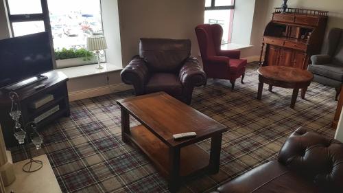 a living room with leather chairs and a coffee table at The Moorings Hotel & Seafood Restaurant in Portmagee