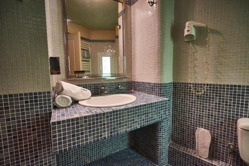 a bathroom with a sink and a mirror and a toilet at Exis Hotel in Athens