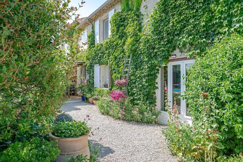 un jardín con plantas y flores frente a un edificio en Chambres d'Hôtes et Gîtes Le Mas Mellou, en Orange