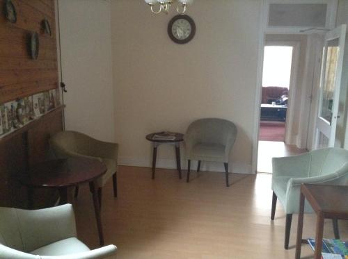 a room with chairs and a table and a clock on the wall at Park House Guest House in Warwick