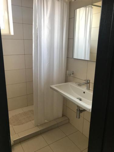 baño con cortina de ducha blanca y lavamanos en Neopolis en Polyana