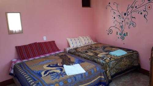 2 camas individuales en una habitación con paredes rosas en Hospedaje Lolita en San Pedro La Laguna